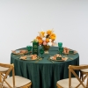 Okrągły stół weselny z obrusem welurowym w kolorze butelkowej zieleni, złote kandelabry i białe kwiaty – luksusowy wynajem tekstyliów na eventy i wesela