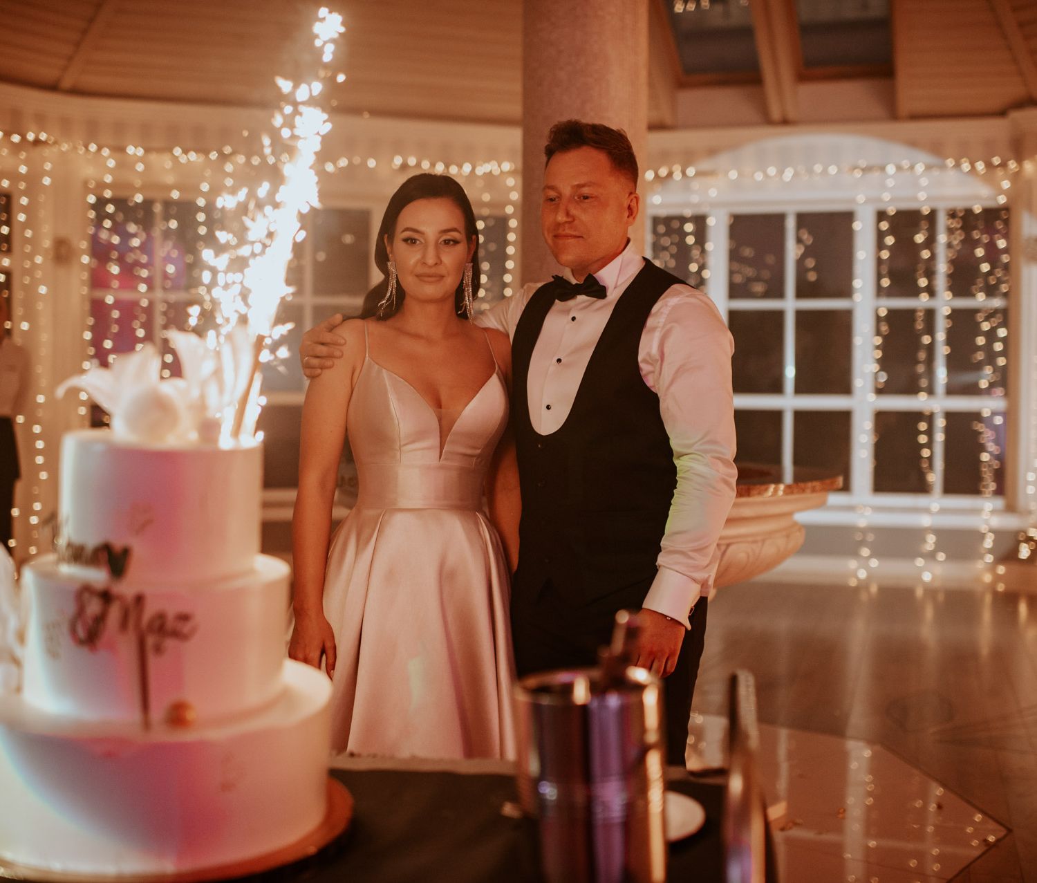 tort weselny krojenie tortu najlepszy tort na wesele girlandy żarówkowe wesele i ślub wynajem dekoracji wynajem artykułów dekoracyjnych Fot: Imagine Weddings