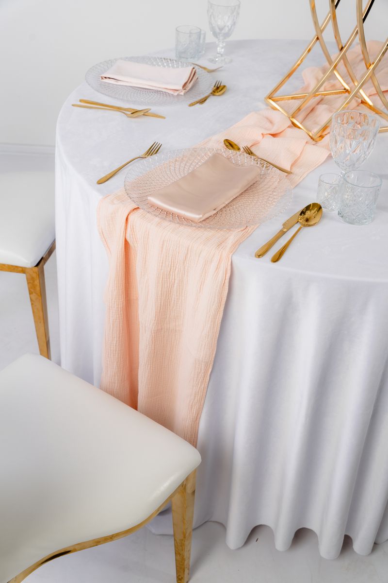 Detal łososiowego bieżnika muślinowego o gniecionej teksturze – bawełniana tkanina w kolorze Peach Fuzz na wynajem, naturalny materiał eventowy