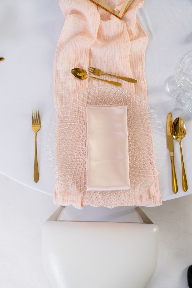 Romantyczna dekoracja stołu z łososiowym bieżnikiem muślinowym, złotą zastawą i kwiatami – wypożyczalnia tekstyliów weselnych w stylu Fine Art