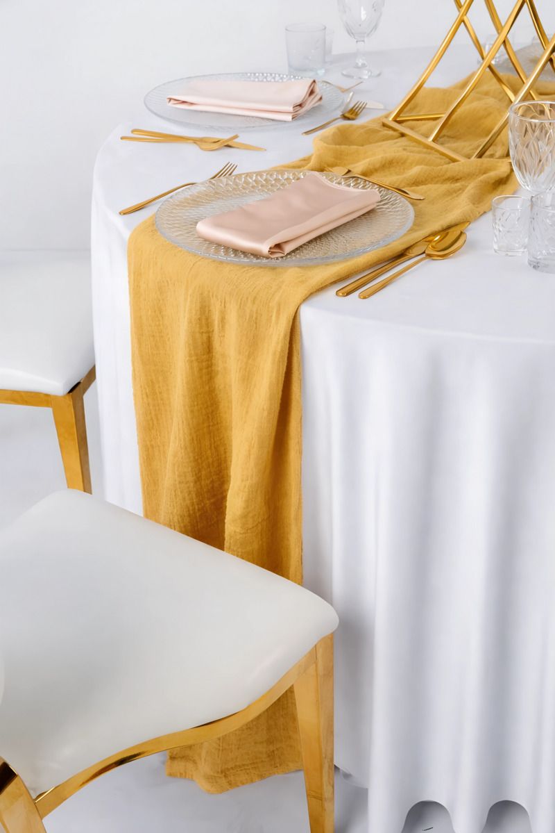 Miodowy bieżnik muślinowy o gniecionej strukturze udrapowany na drewnianym stole – słoneczna dekoracja weselna w stylu Tuscany i Boho, wynajem tekstyliów eventowych