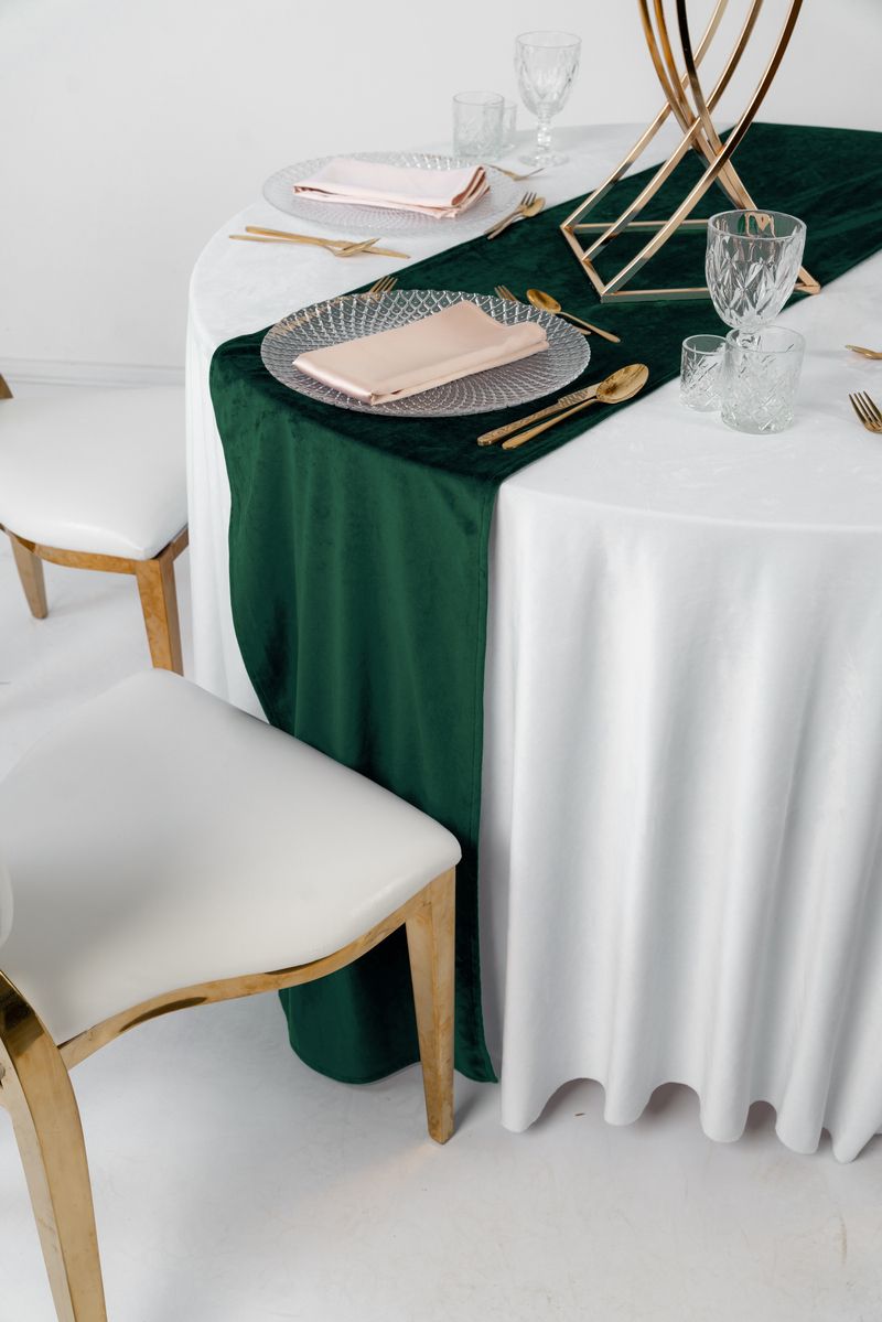 Dekoracja stołu weselnego z bieżnikiem welurowym w kolorze butelkowej zieleni, złotą zastawą i białymi kwiatami – styl Modern Glamour, luksusowy wynajem tekstyliów