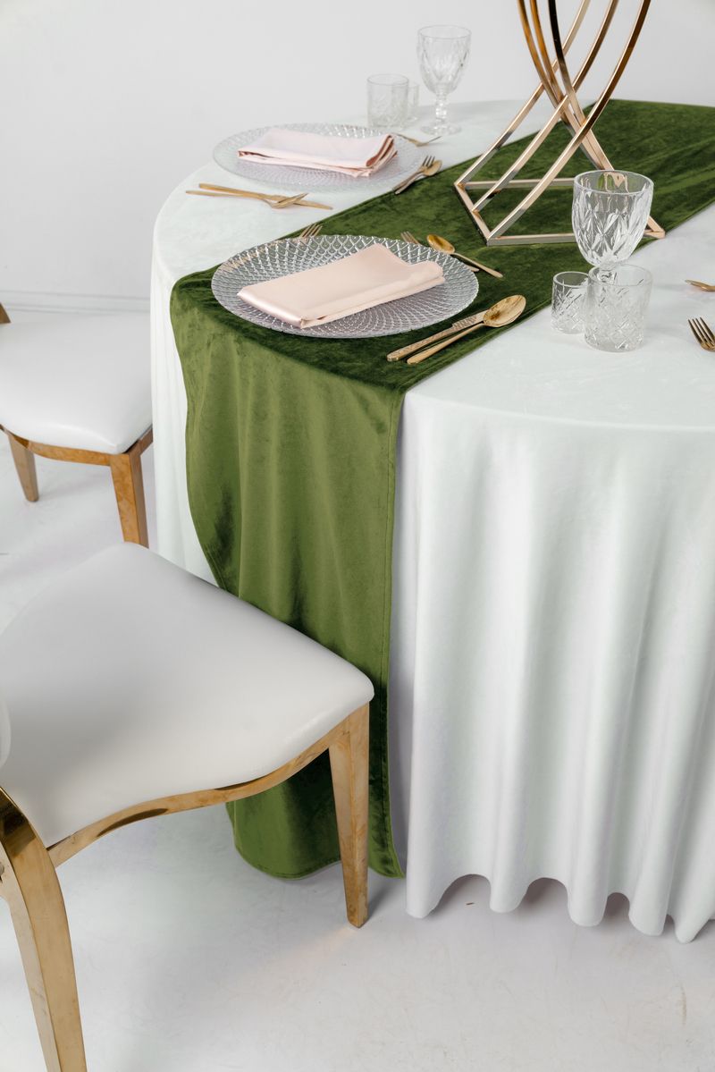 Oliwkowy bieżnik welurowy na surowym drewnianym stole, styl Mediterranean Luxury, mosiężne świeczniki i gałązki oliwne, wypożyczalnia dekoracji premium Olive Green