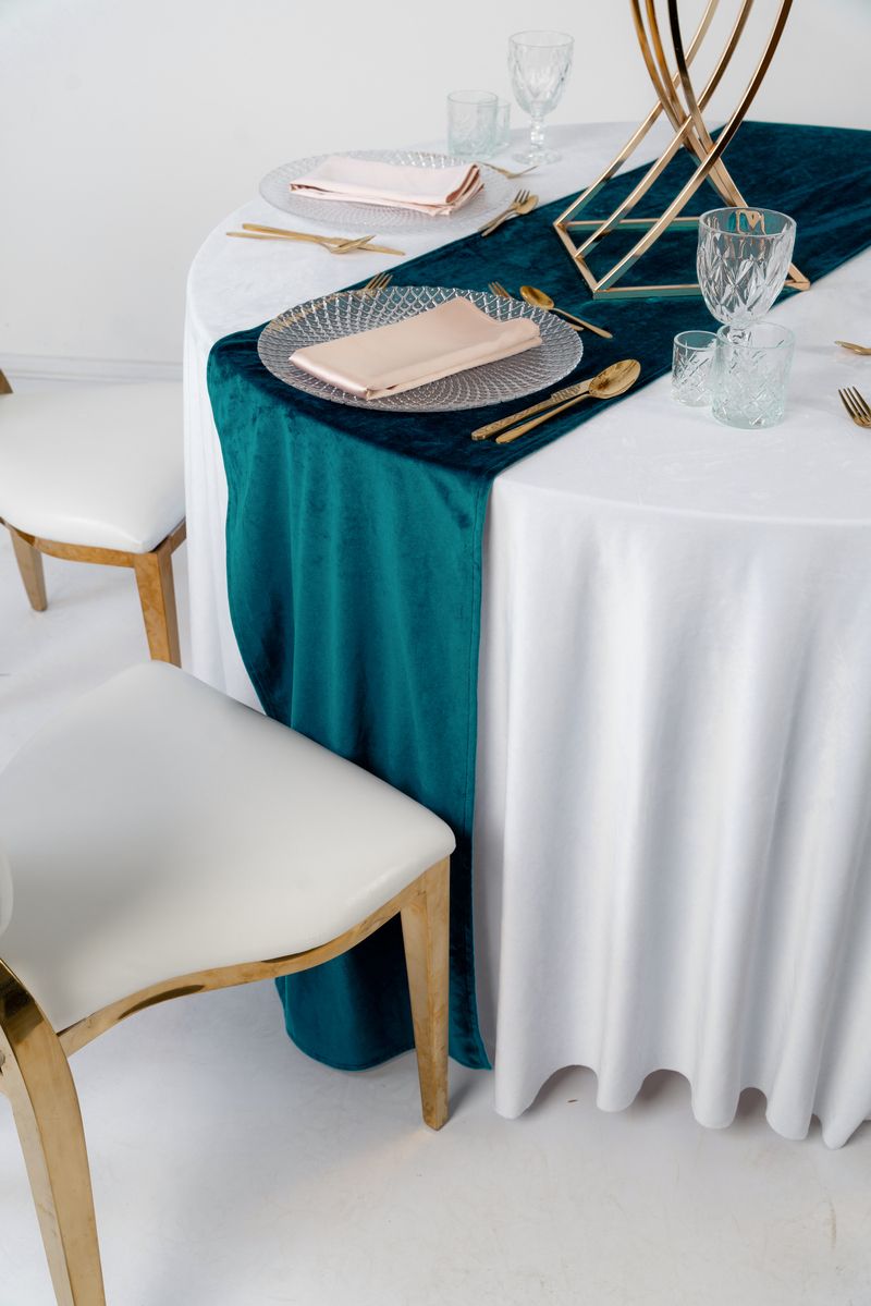 Długi turkusowy bieżnik welurowy na drewnianym stole weselnym, złota zastawa i biała porcelana – styl Modern Mediterranean, luksusowa wypożyczalnia tekstyliów eventowych Teal Velvet