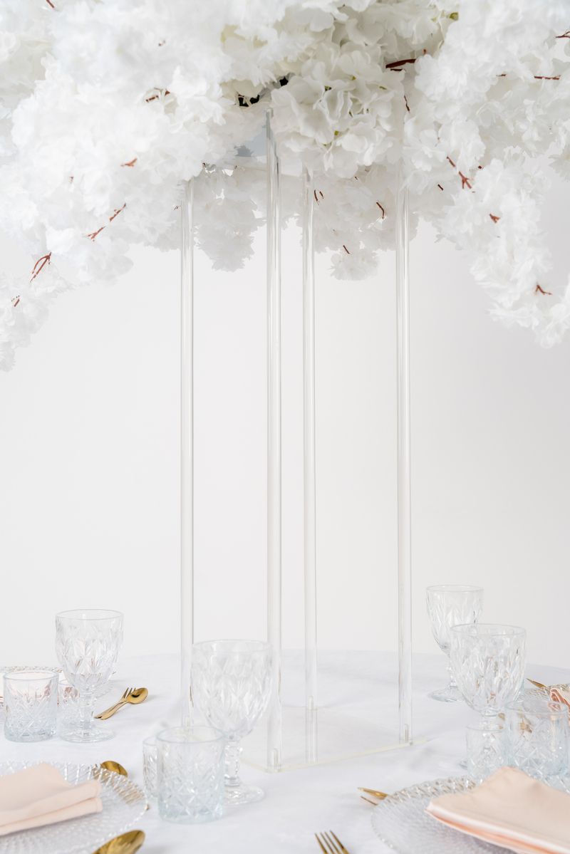 Przezroczysty stojak na kwiaty w stylu modern glamour – wysoki kwietnik geometryczny, który nie zasłania gości przy stole.