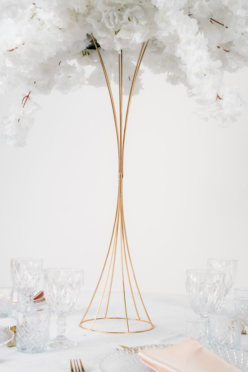 Wysoki złoty kwietnik stożek w stylu glamour – luksusowa dekoracja środka stołu na wesele z kompozycją kwiatową.