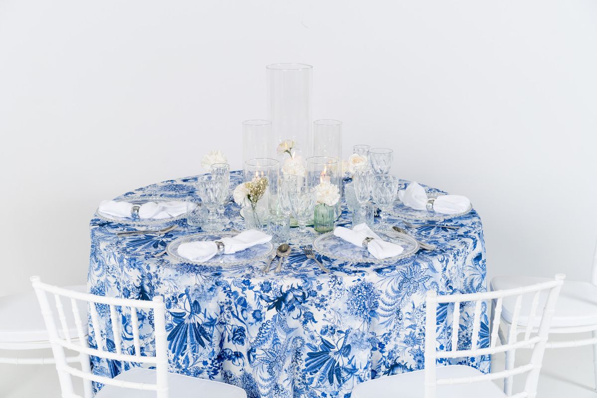 Zbliżenie na wzór kwiatowa łąka niebieska – wysokiej jakości obrus eventowy, detale białych liści i błękitnych kwiatów na tkaninie premium