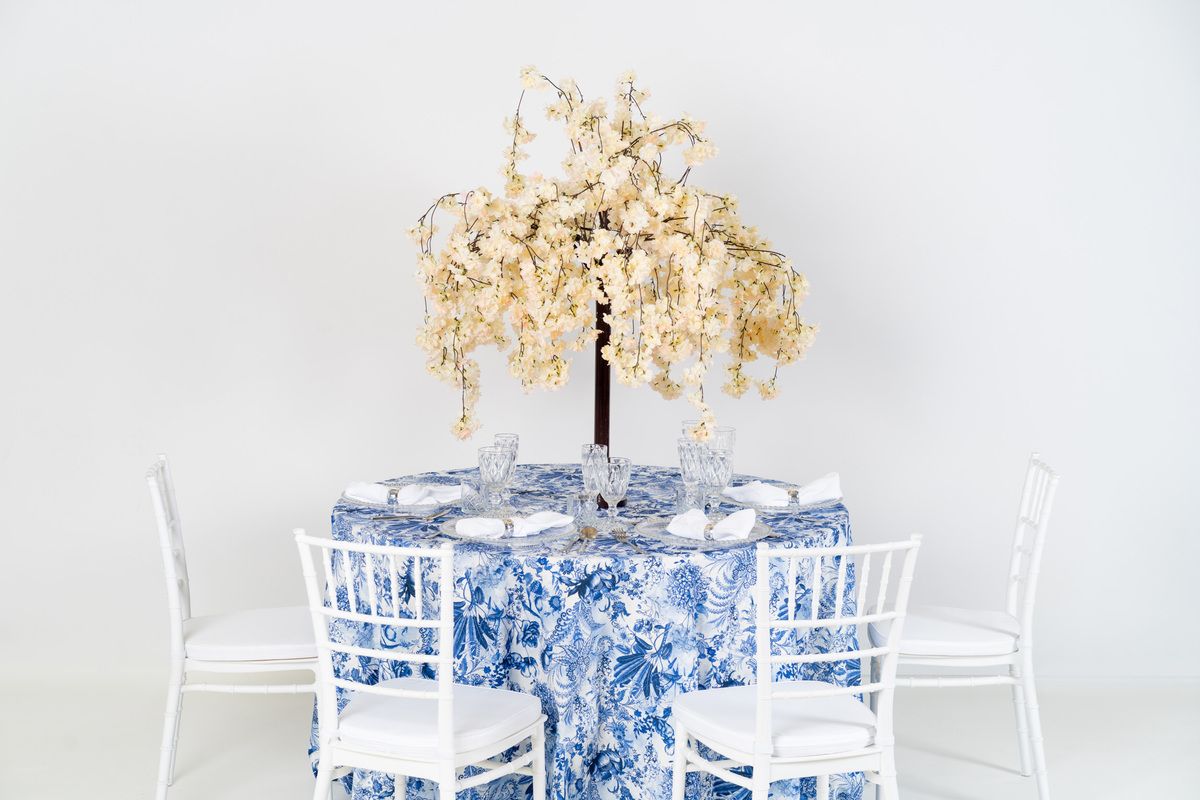 Niebieski obrus w kwiatową łąkę na wynajem – wzorzysta tkanina na wesele w odcieniu dusty blue z białym motywem florystycznym
