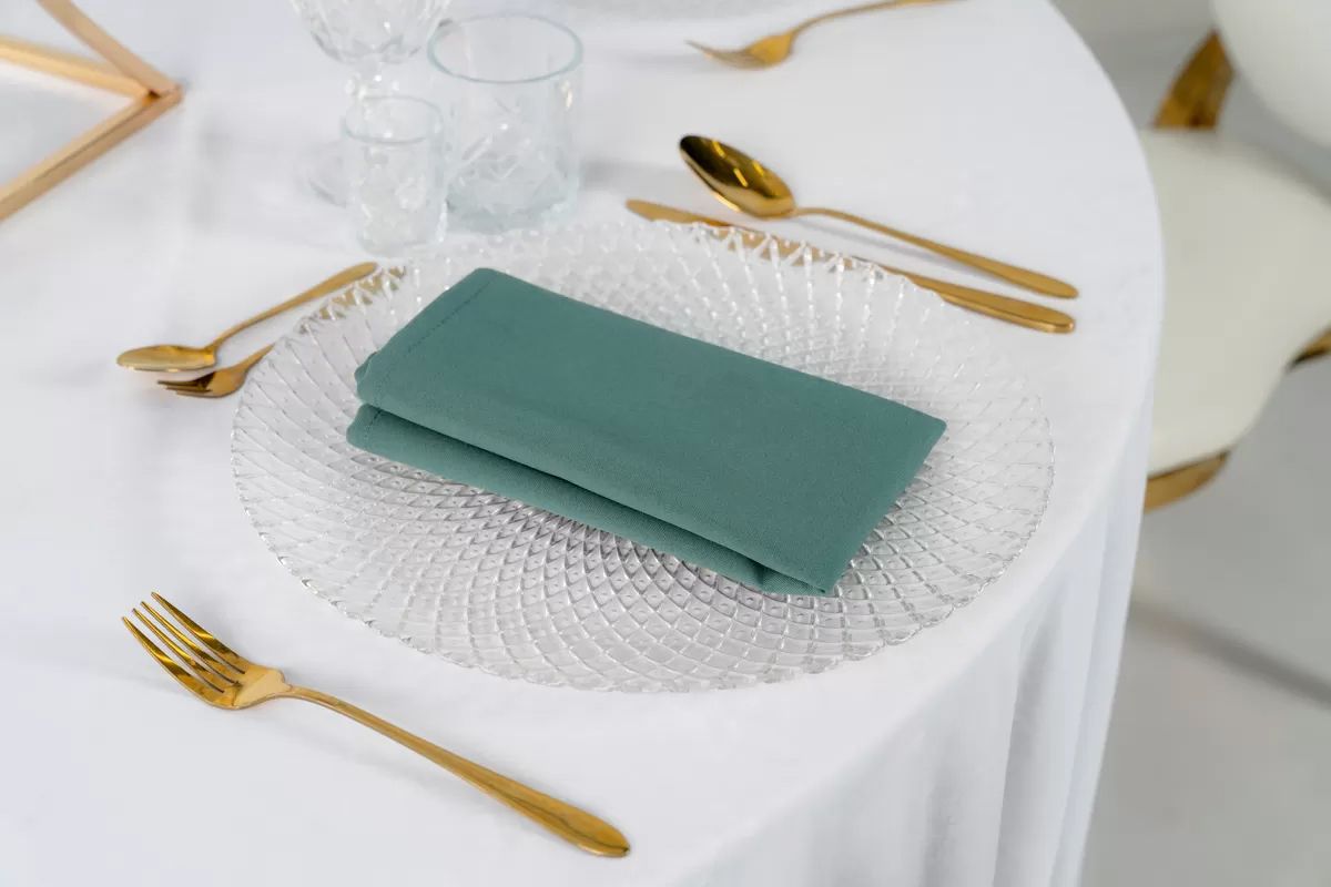 Serwetka poliestrowa w kolorze szałwiowym o matowym wykończeniu ułożona przy złotych sztućcach – elegancka dekoracja stołu weselnego, styl Botanical, wynajem tekstyliów