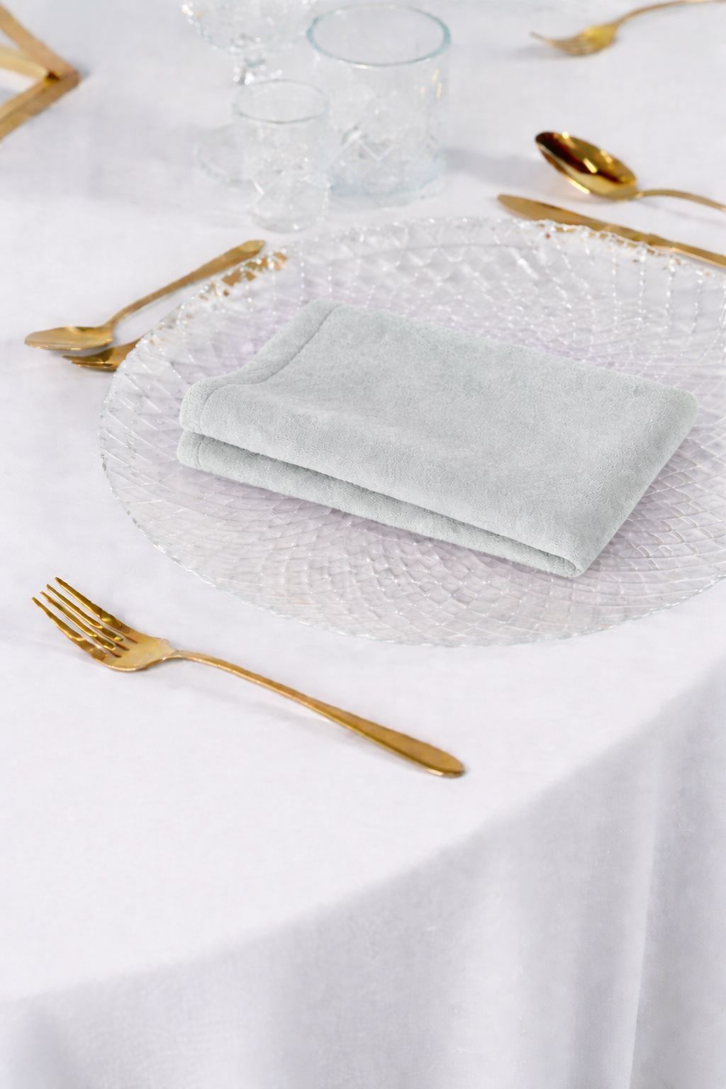 Luksusowa aranżacja stołu weselnego z białymi serwetkami welurowymi, złotymi sztućcami i szklanymi podtalerzami – styl Modern Glamour, wypożyczalnia tekstyliów premium