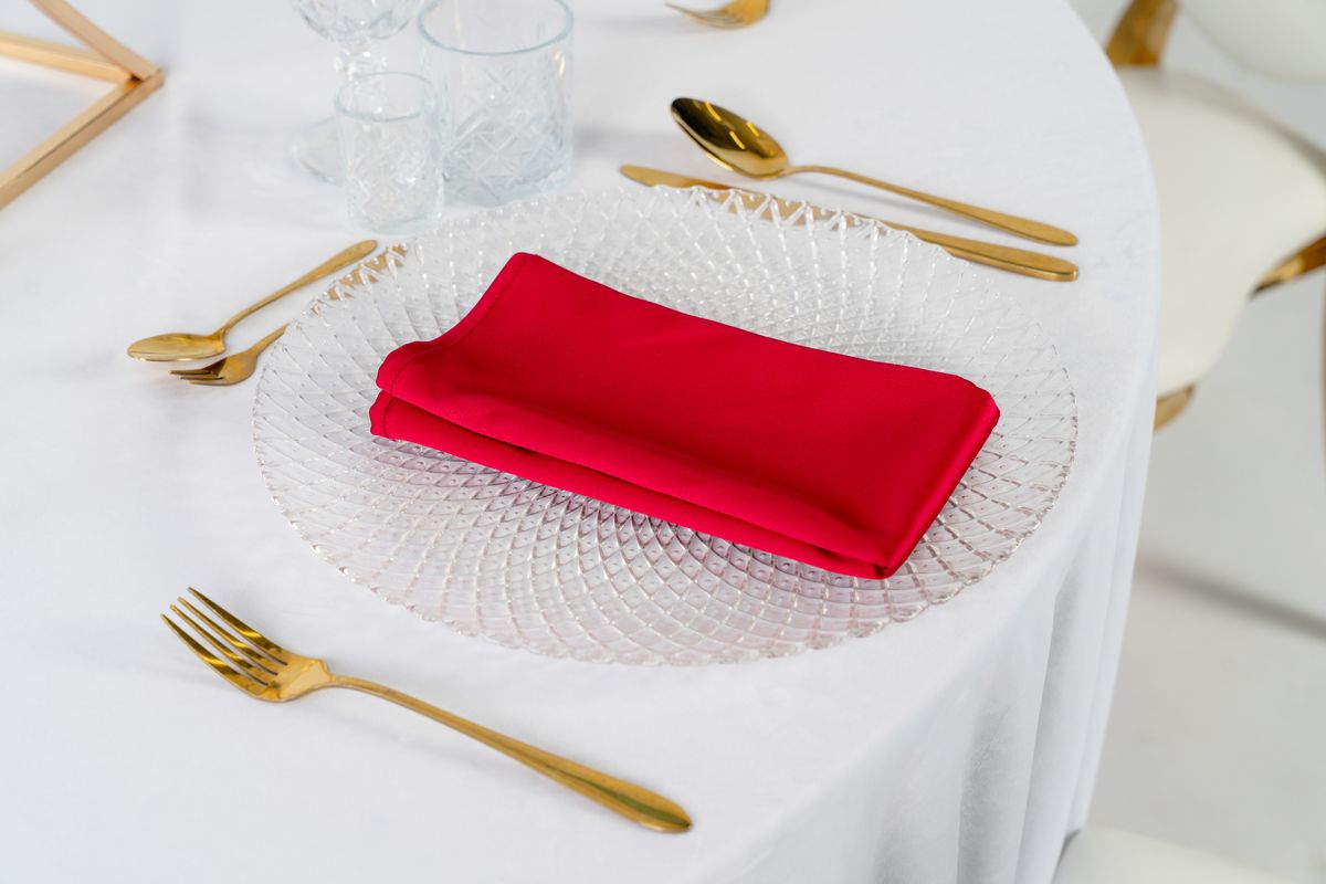 Detal bordowej serwetki z połyskującej satyny – luksusowe tekstylia bankietowe w kolorze głębokiego wina, wypożyczalnia dekoracji.
