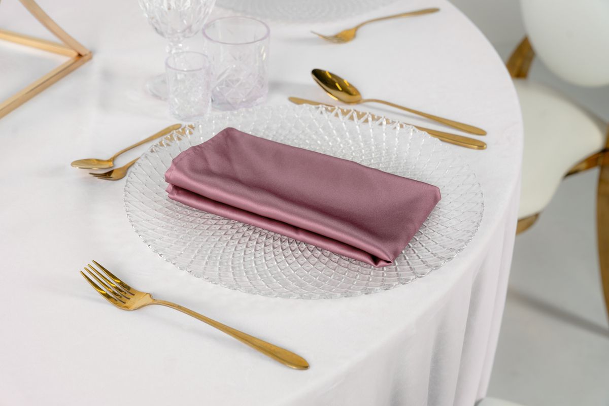 Elegancka satynowa serwetka dusty pink na złotym podtalerzu – dekoracja stołu weselnego w stylu Modern Glamour
